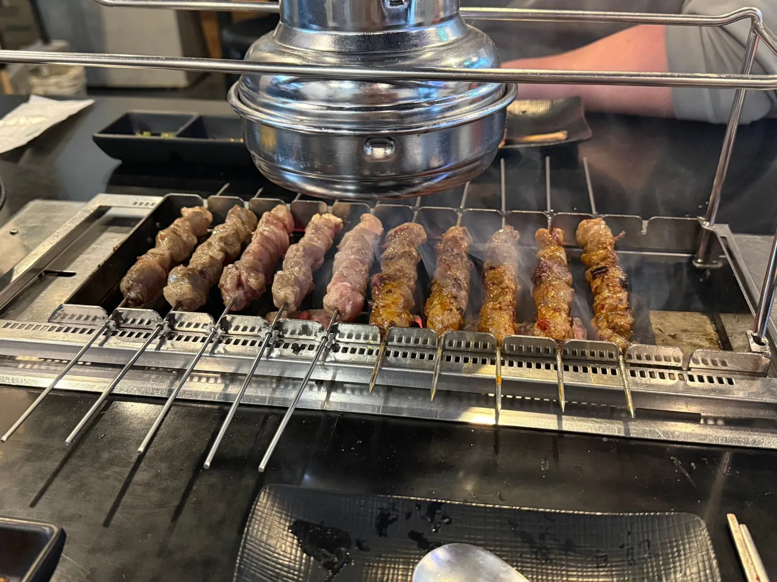 Lamb skewers hanging in a row and cooking over charcoal