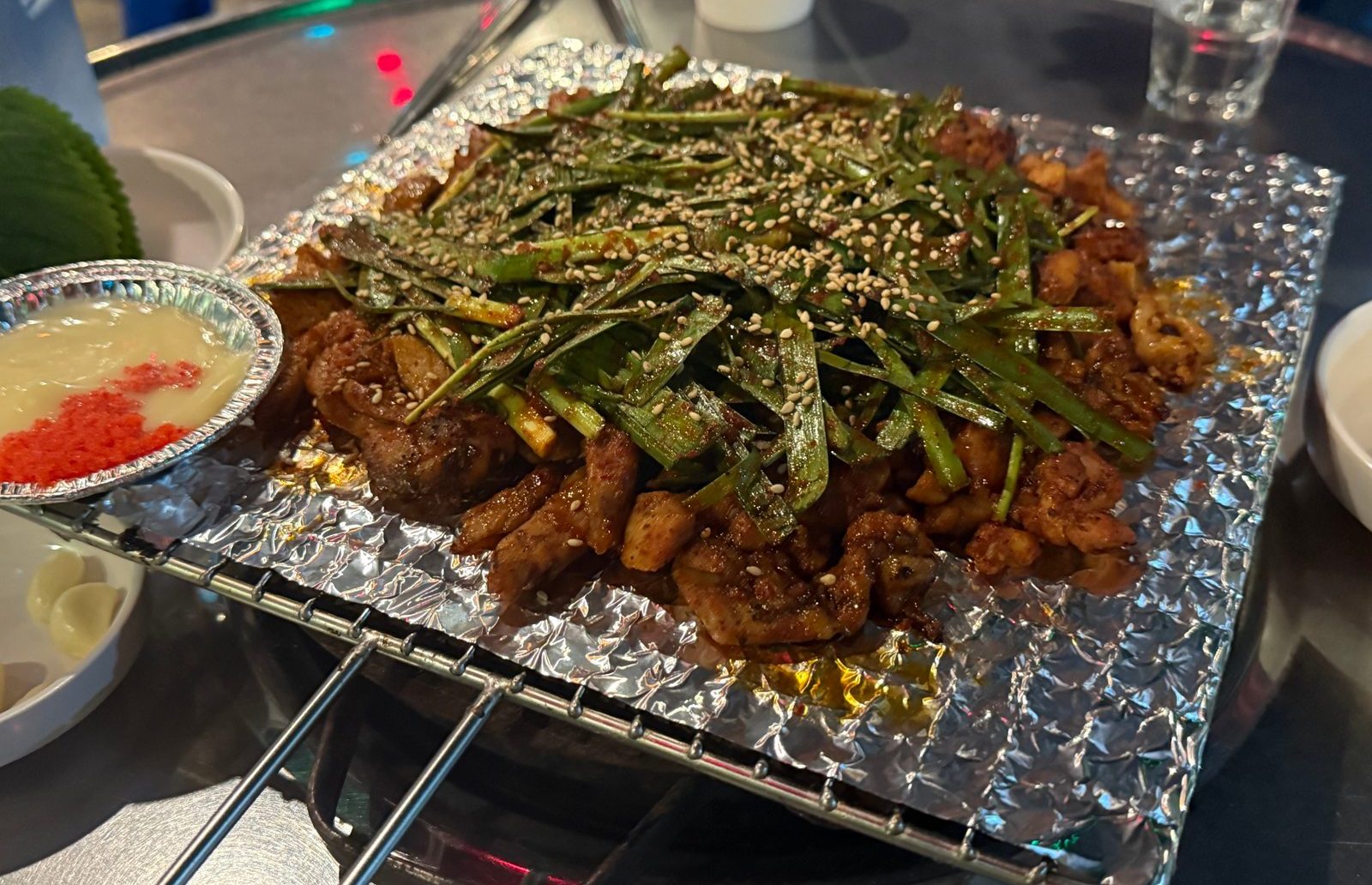 은박 받침 위에 부추를 수북이 얹은 숯불 닭구이