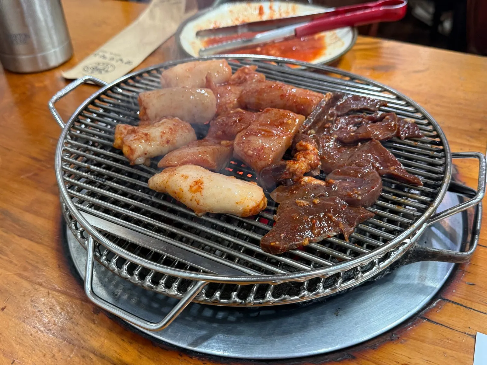둥근 석쇠 위에서 익고 있는 양념한 특양과 대창