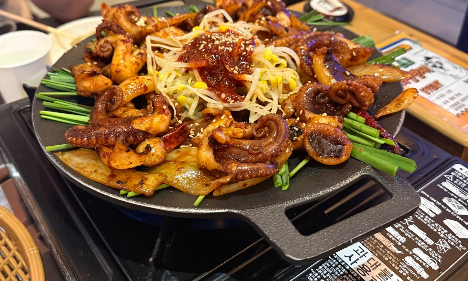 Seasoned webfoot octopus on a black iron plate with chives and bean sprouts