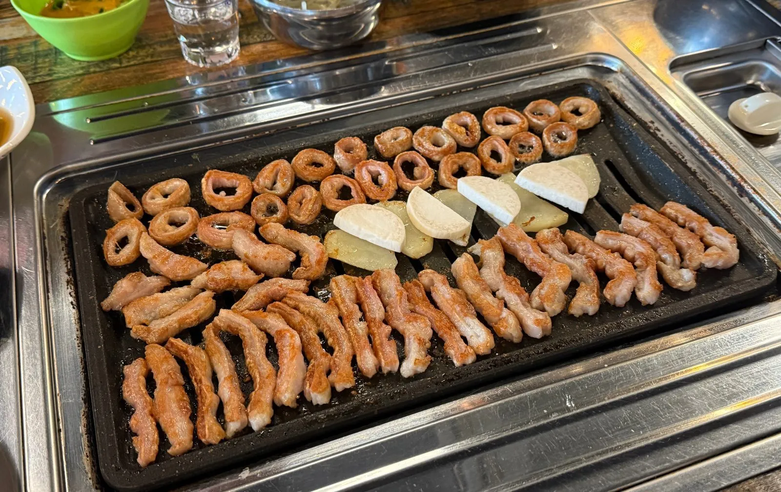 Makchang and rice cakes lined up on a square grill plate