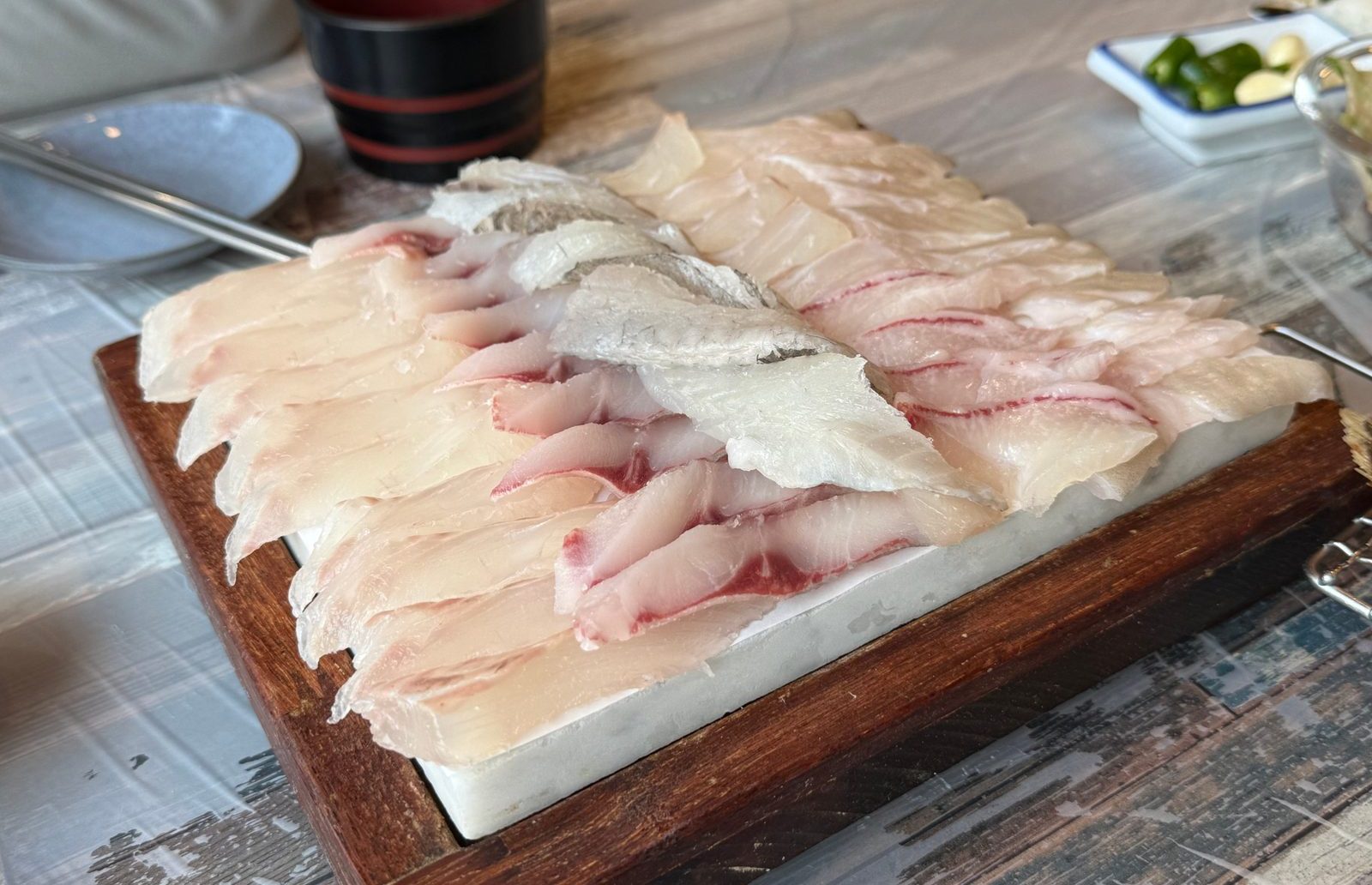 나무 도마 위에 가지런히 놓인 도톰한 흰살 생선회