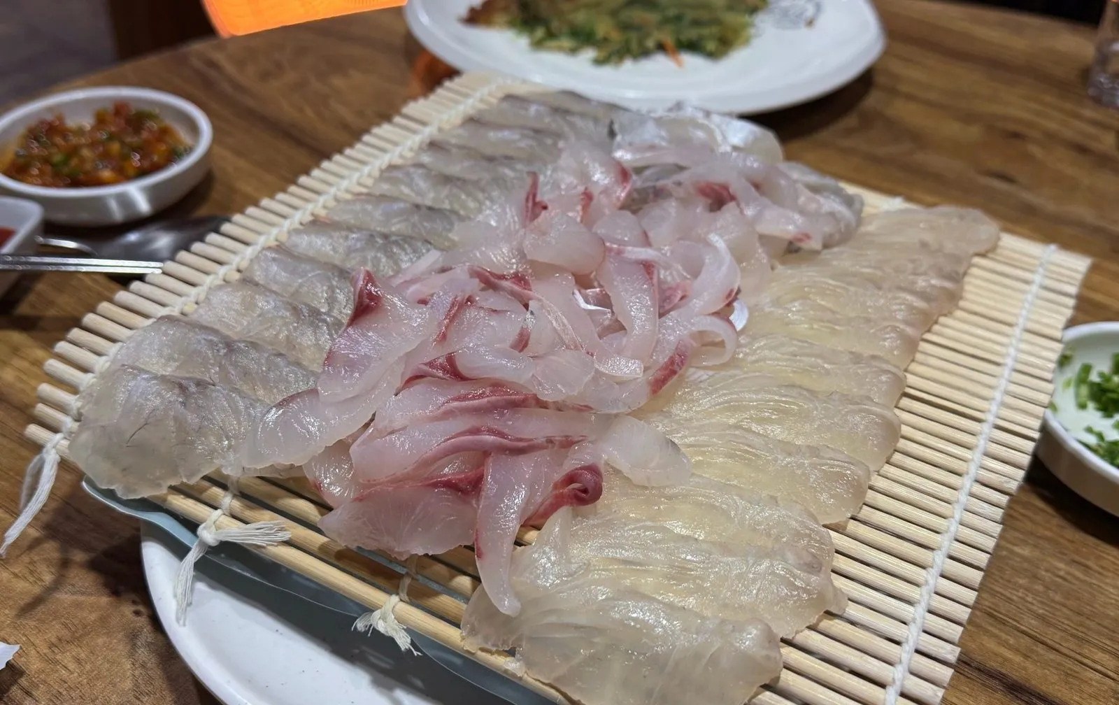 Assorted sashimi spread out lengthwise on a bamboo mat