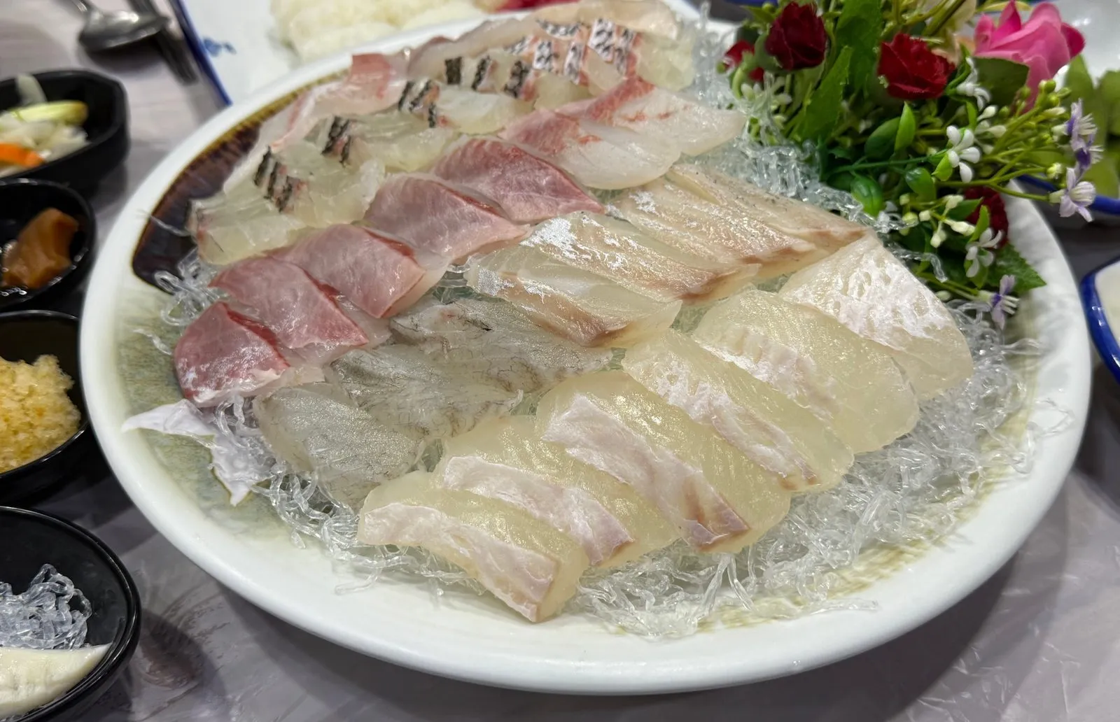 Assorted sashimi from several kinds of fish on a large plate decorated with flowers
