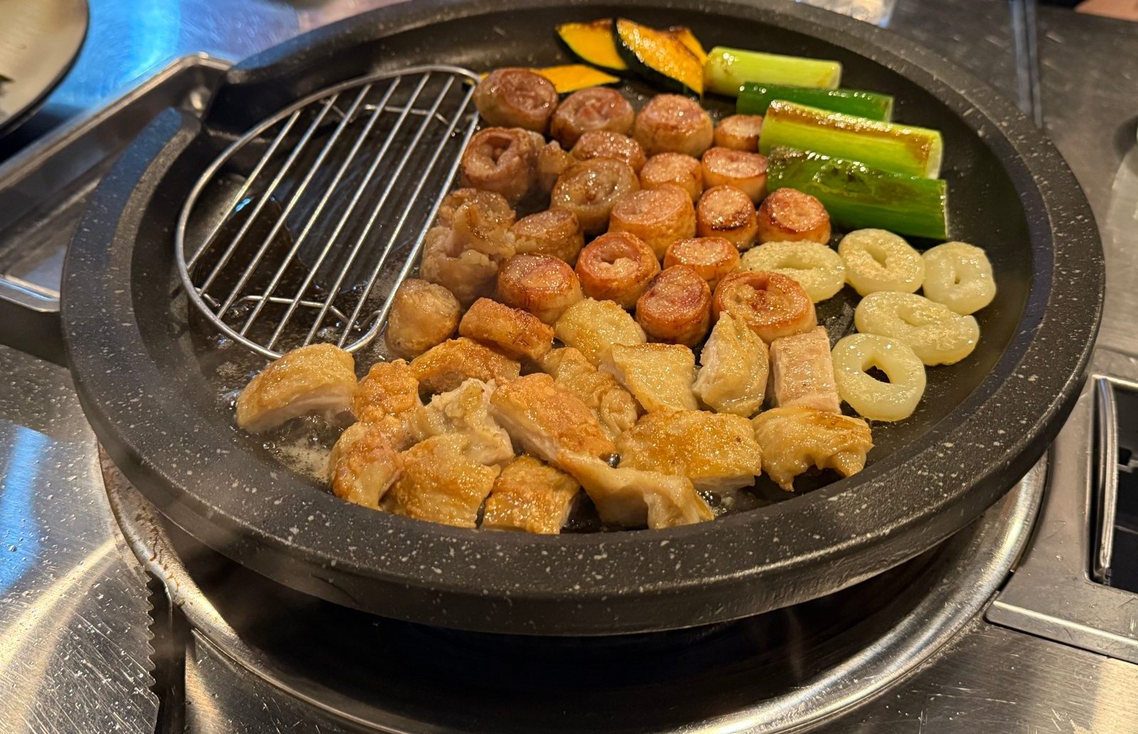 둥근 불판 위에서 익고 있는 막창과 호박, 대파