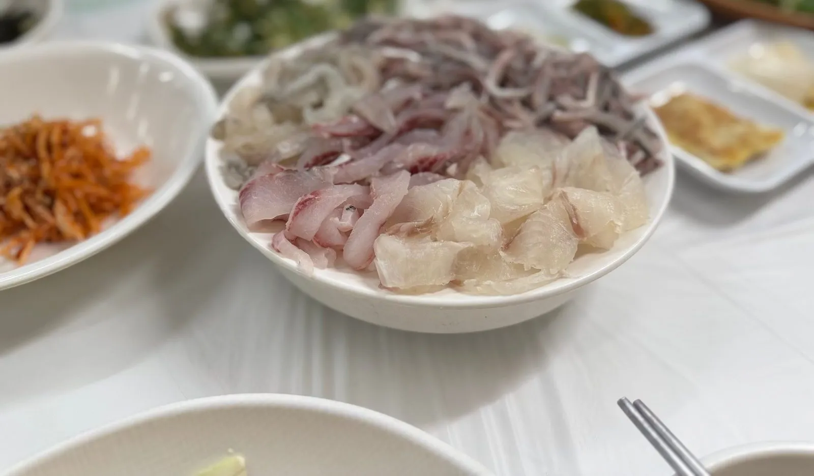 흰 그릇에 수북이 담긴 모듬회와 전어회
