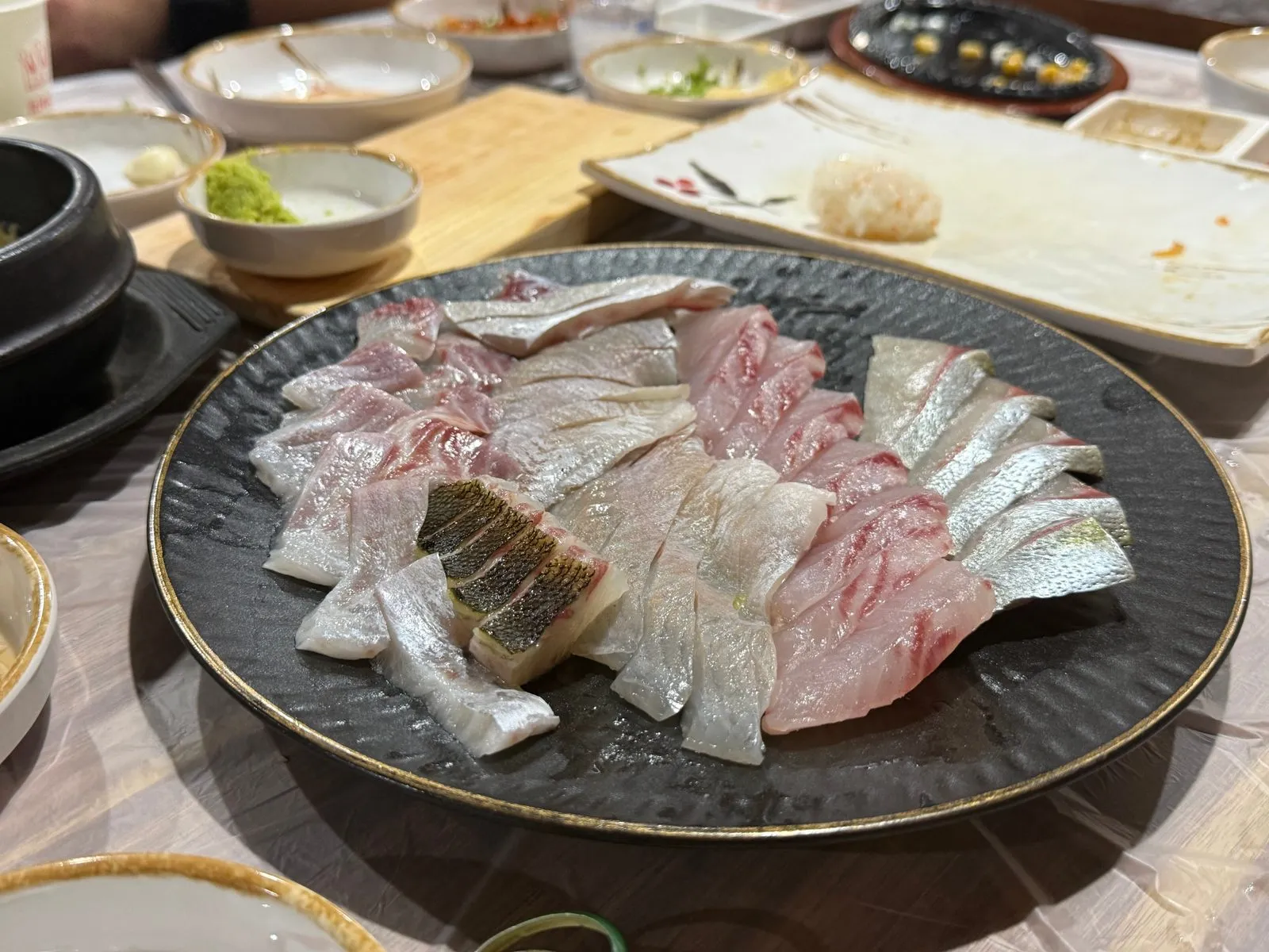 Sashimi from several kinds of fish layered on a black plate