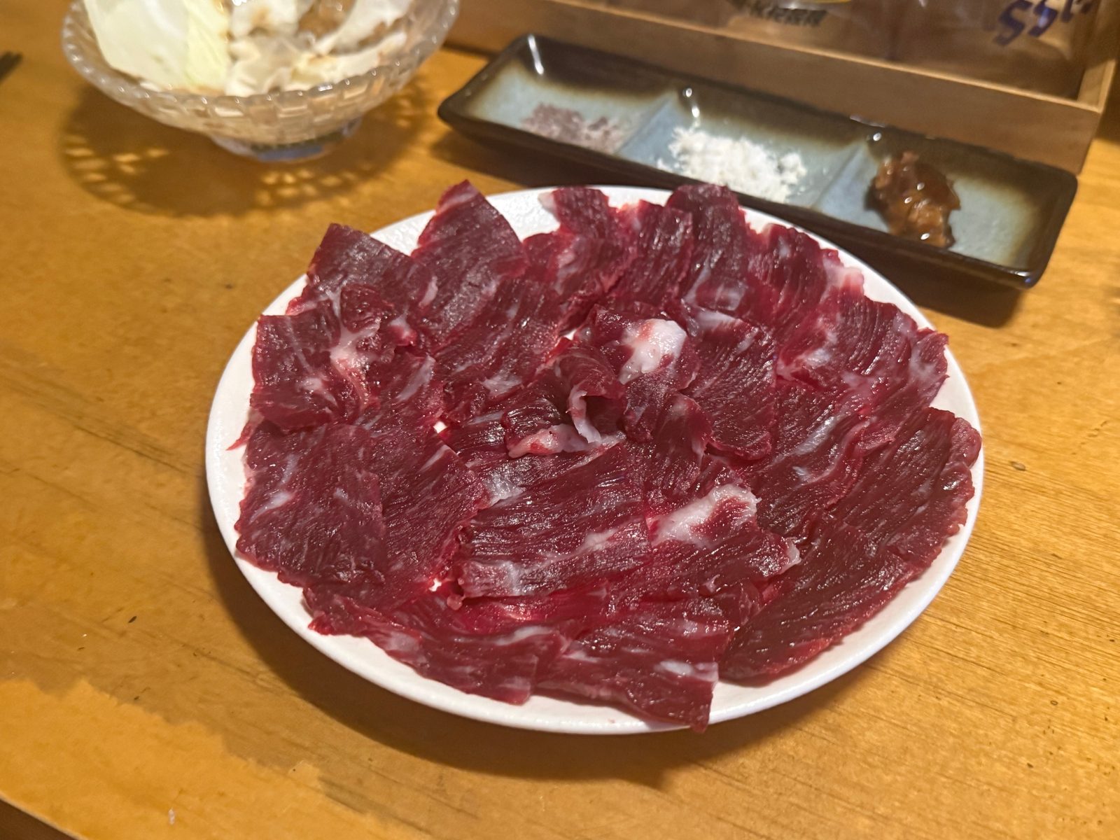 Thin slices of red raw beef spread on a white plate