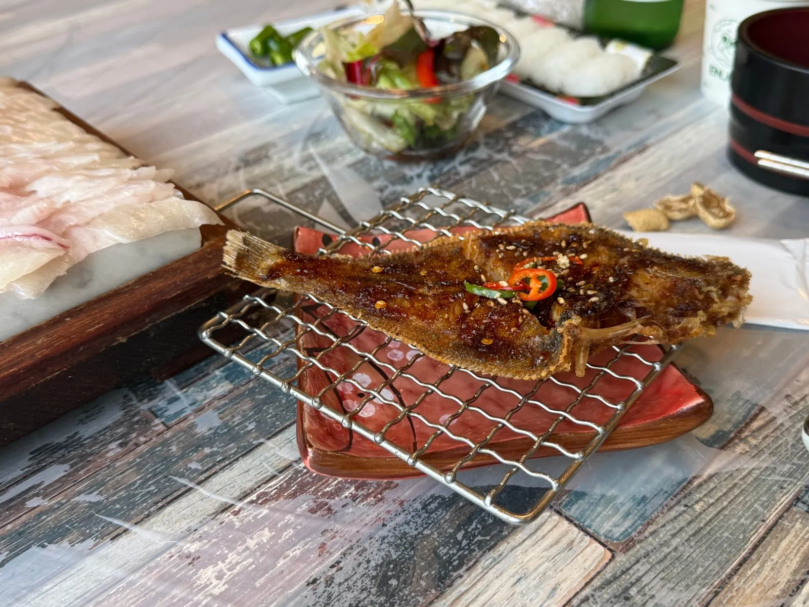 A grilled flounder with seasoning on a wire rack