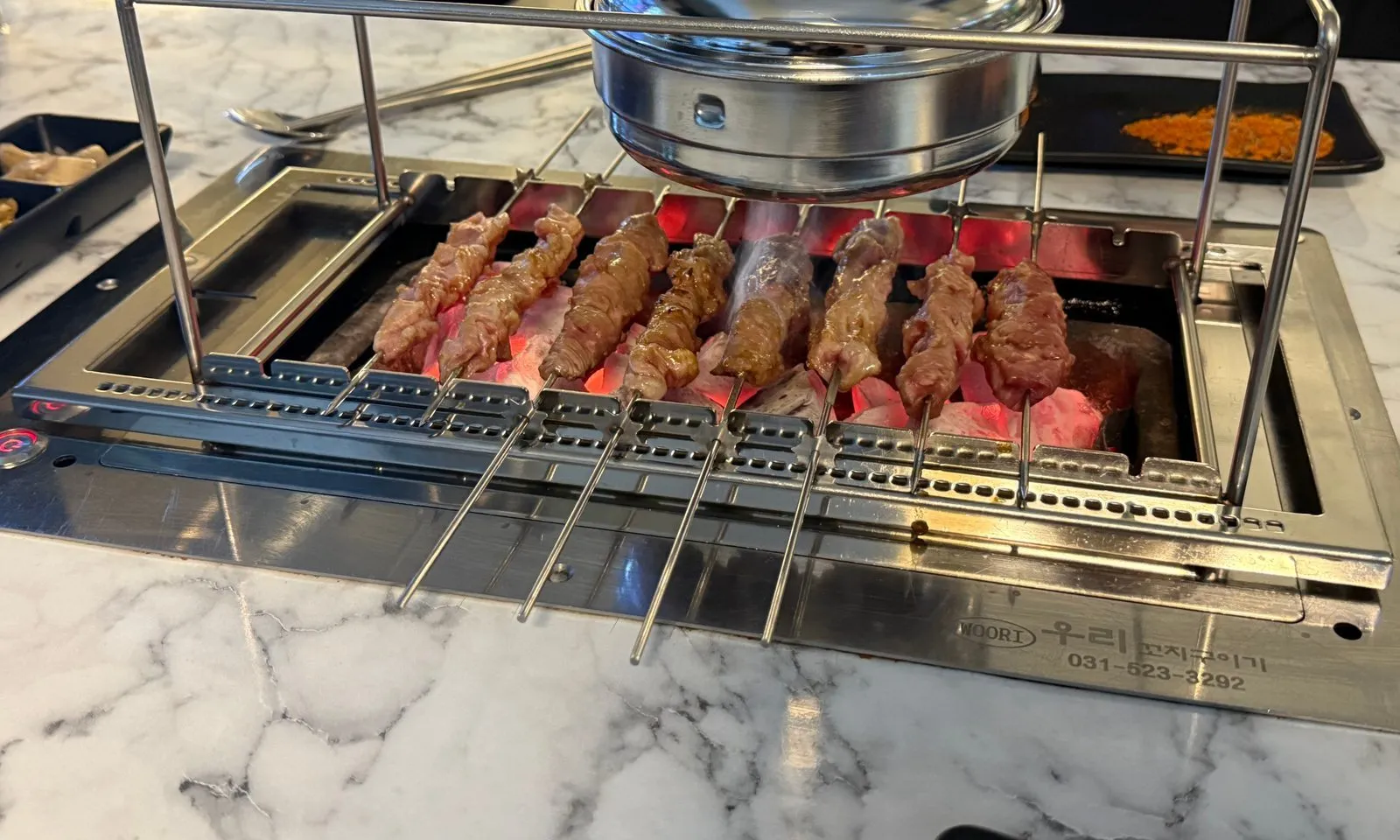 Lamb skewers cooking side by side on a rotating rack over a charcoal grill