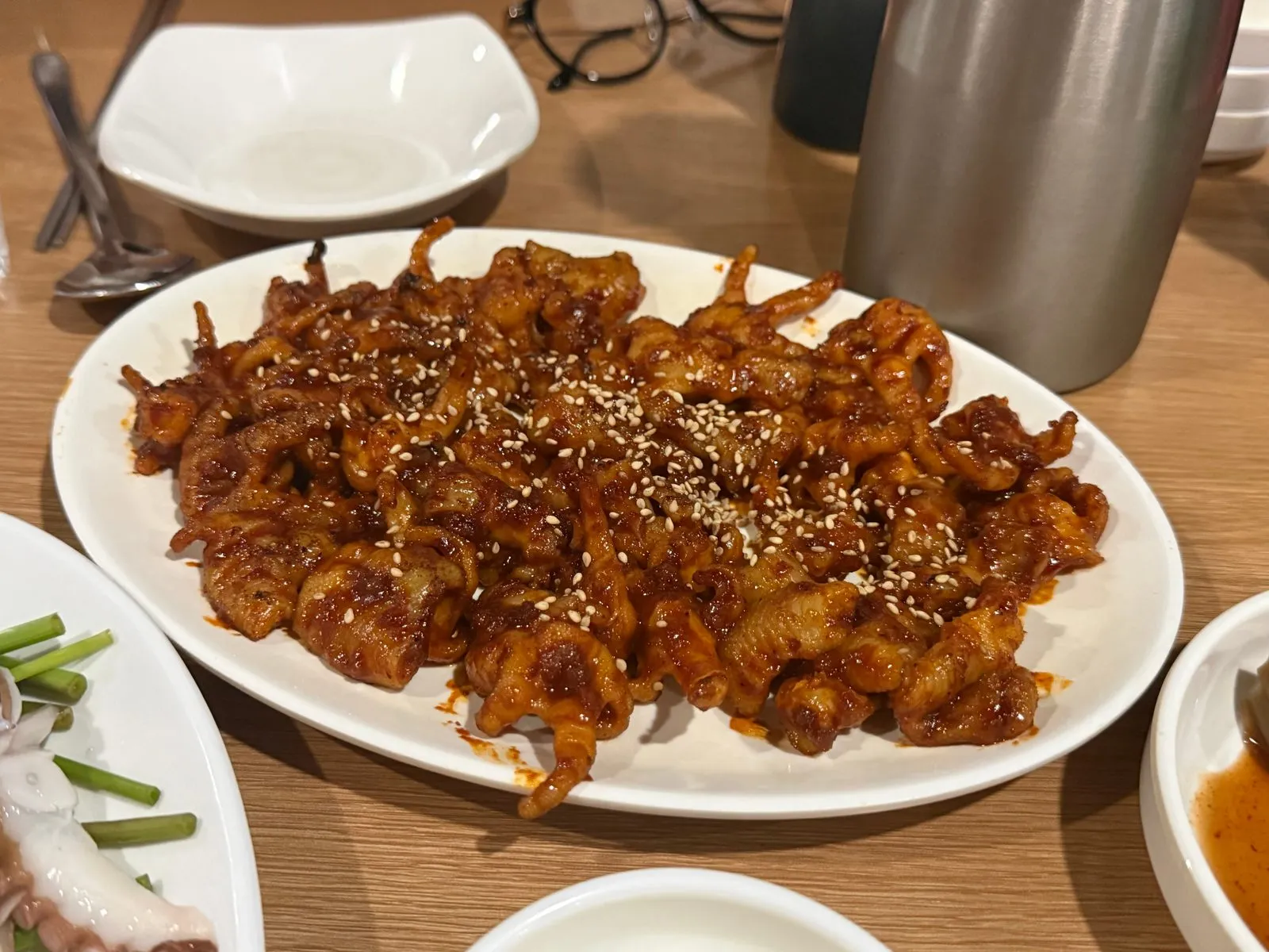 Seasoned boneless chicken feet on a white plate, sprinkled with sesame