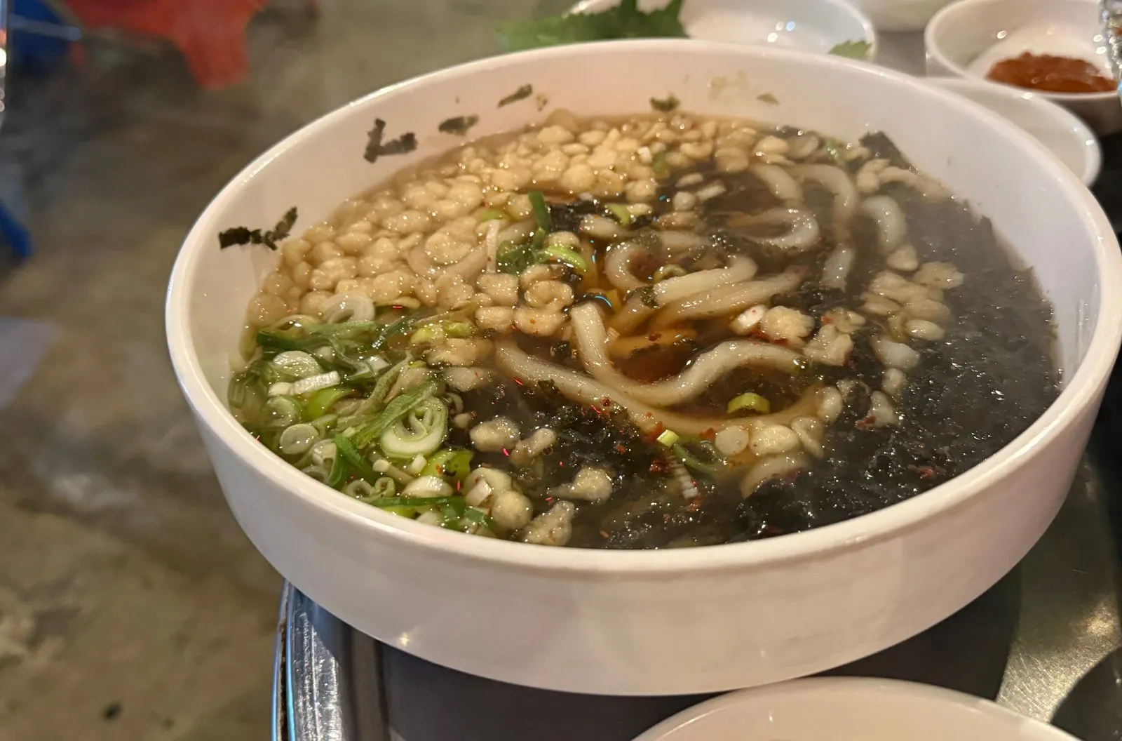 흰 그릇에 담긴 우동과 그 위에 올린 김가루와 파