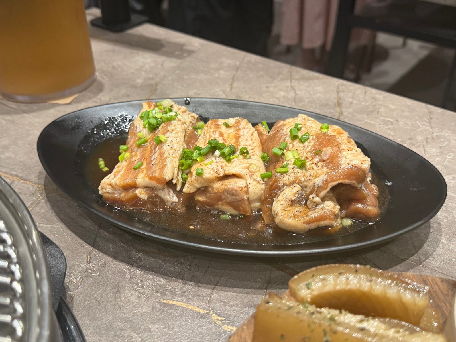 검은 접시에 담겨 나온 양념갈비와 그 위에 뿌린 파