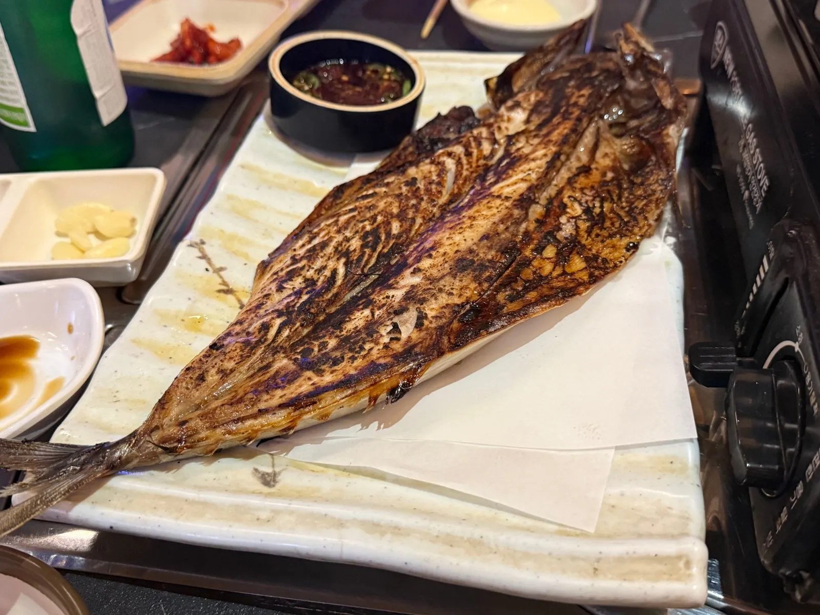 흰 접시에 놓인 반으로 갈라 구운 고등어