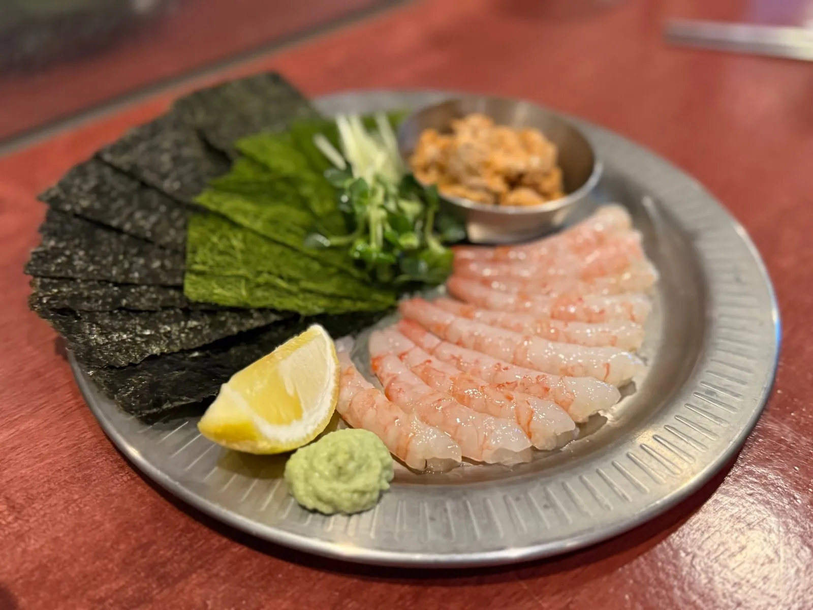 Sweet shrimp, seaweed, wasabi, and a lemon wedge on a silver plate