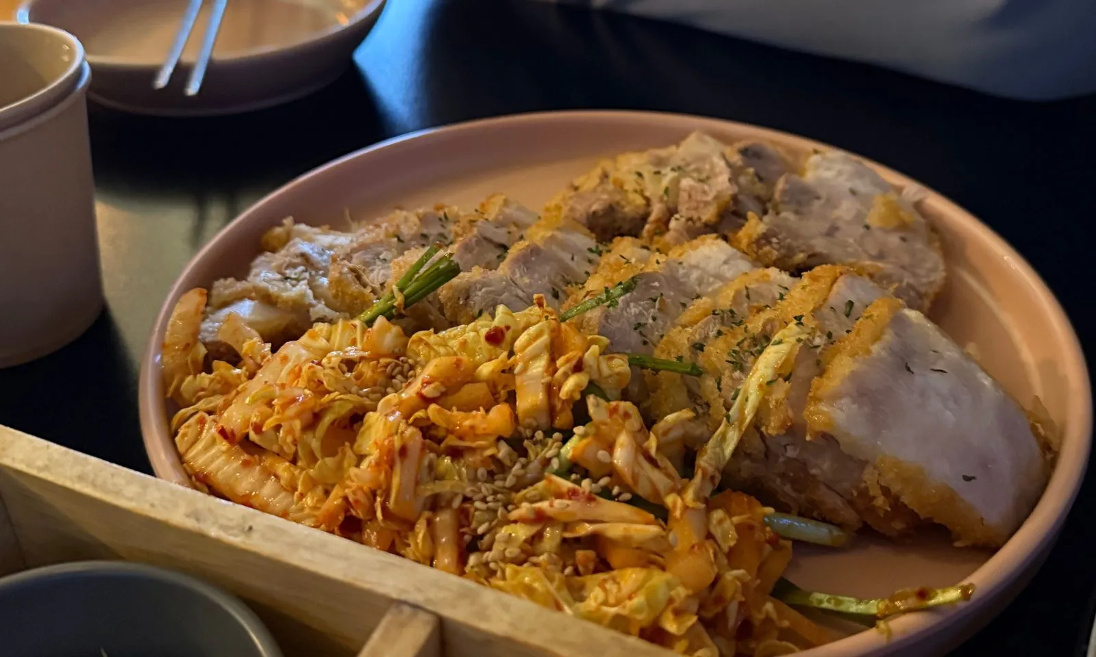 Sliced suyuk katsu on a wide plate with a seasoned vegetable salad