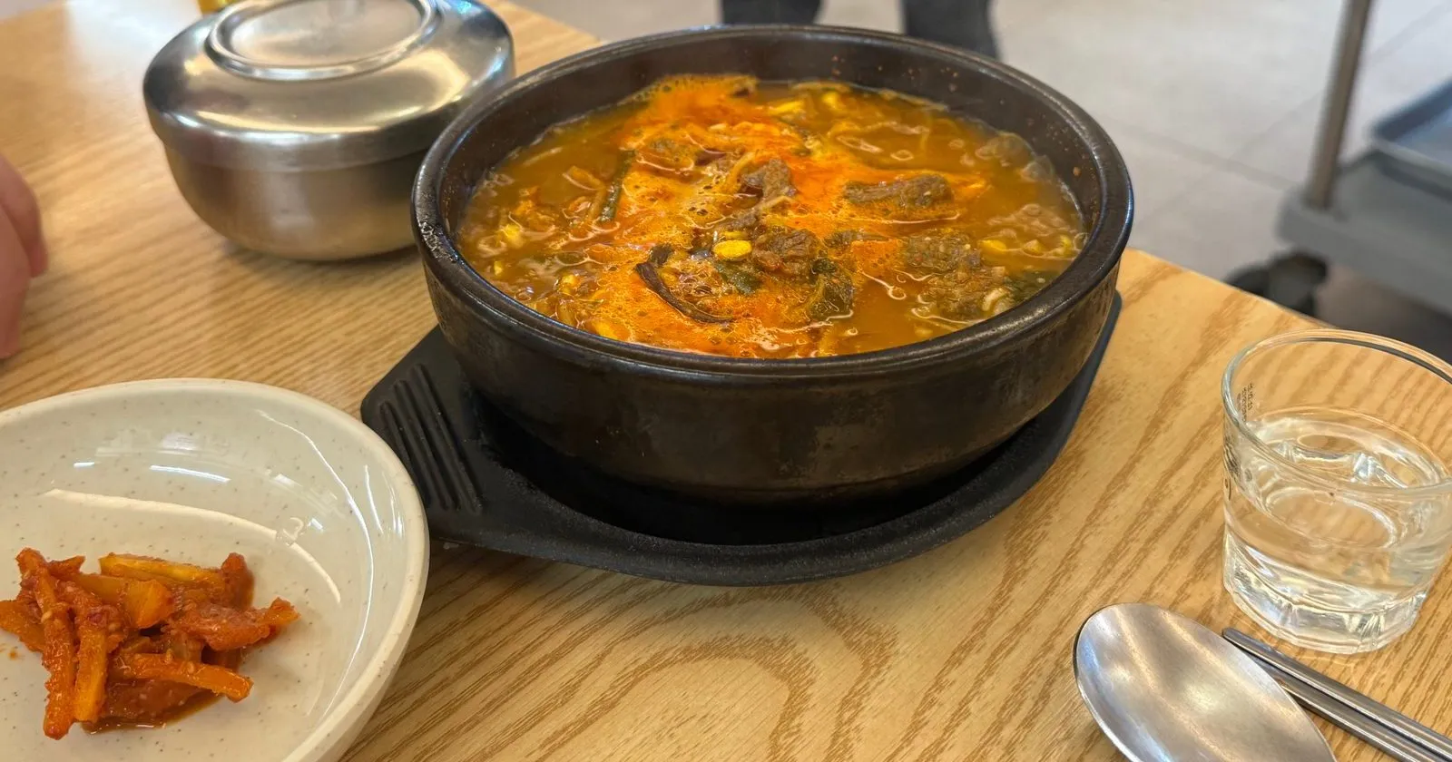 Korean beef soup with red broth in an earthenware pot, with radish kimchi