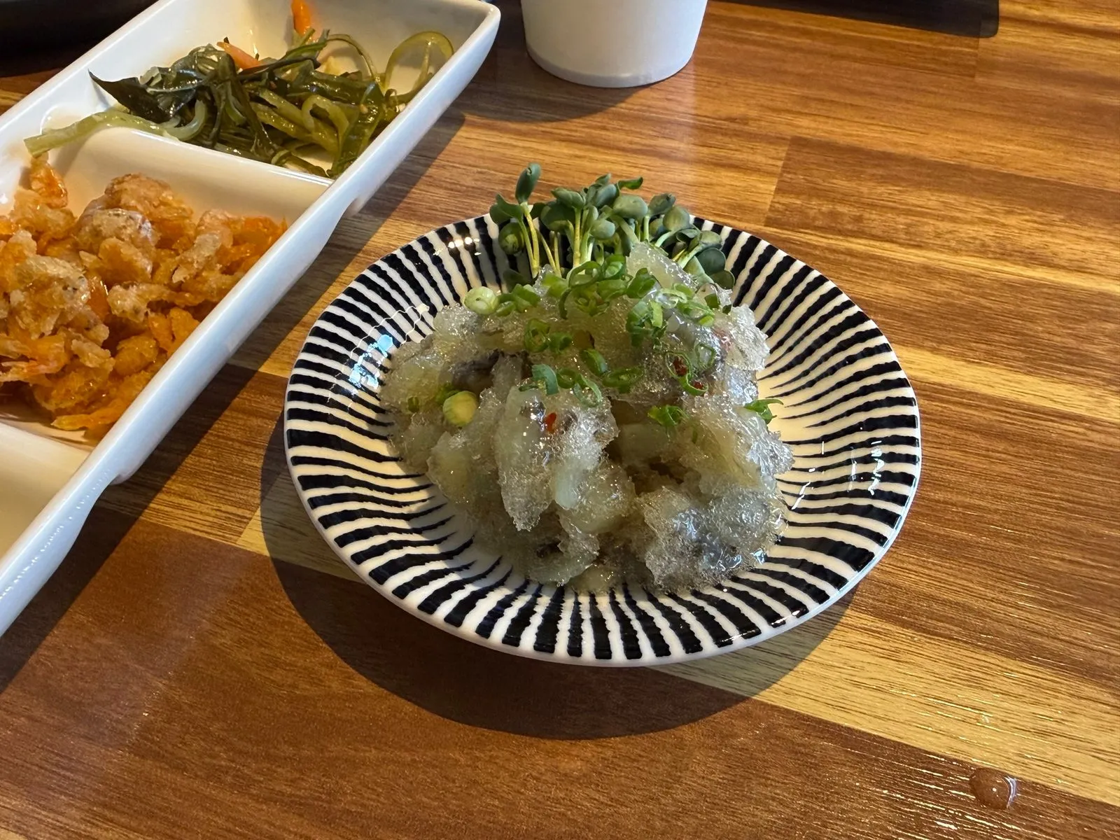 Tako wasabi in a striped bowl topped with sprouts