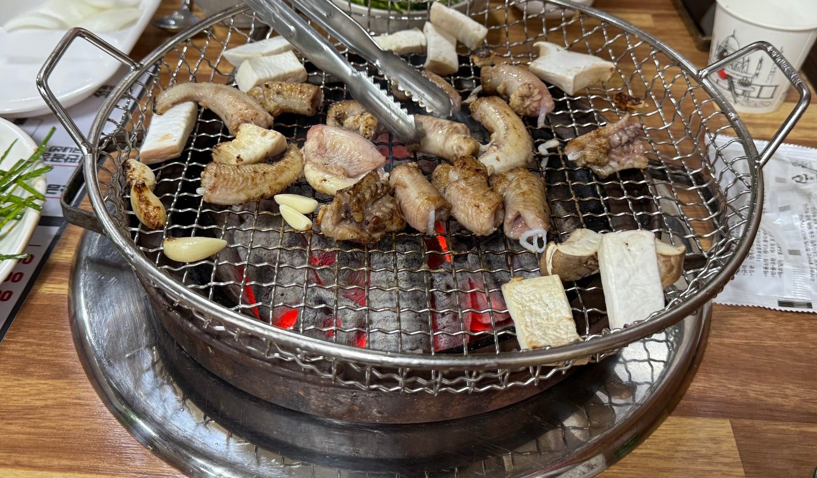 Salt-grilled hagfish cooking on a wire grill over charcoal