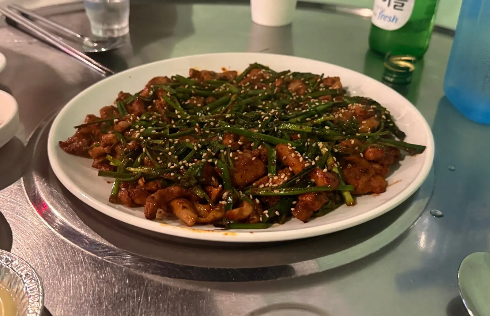 Seasoned grilled chicken on a white plate, piled with chives