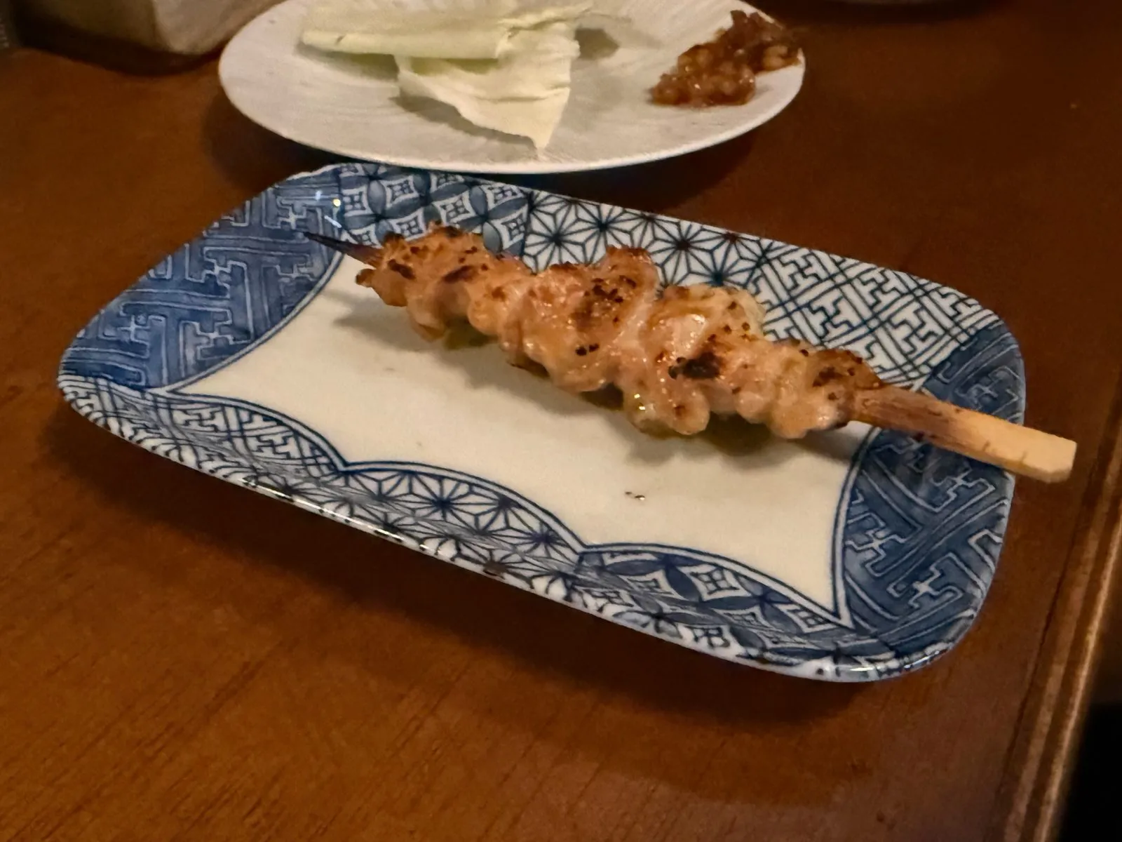 A single chicken skin skewer on a blue patterned plate