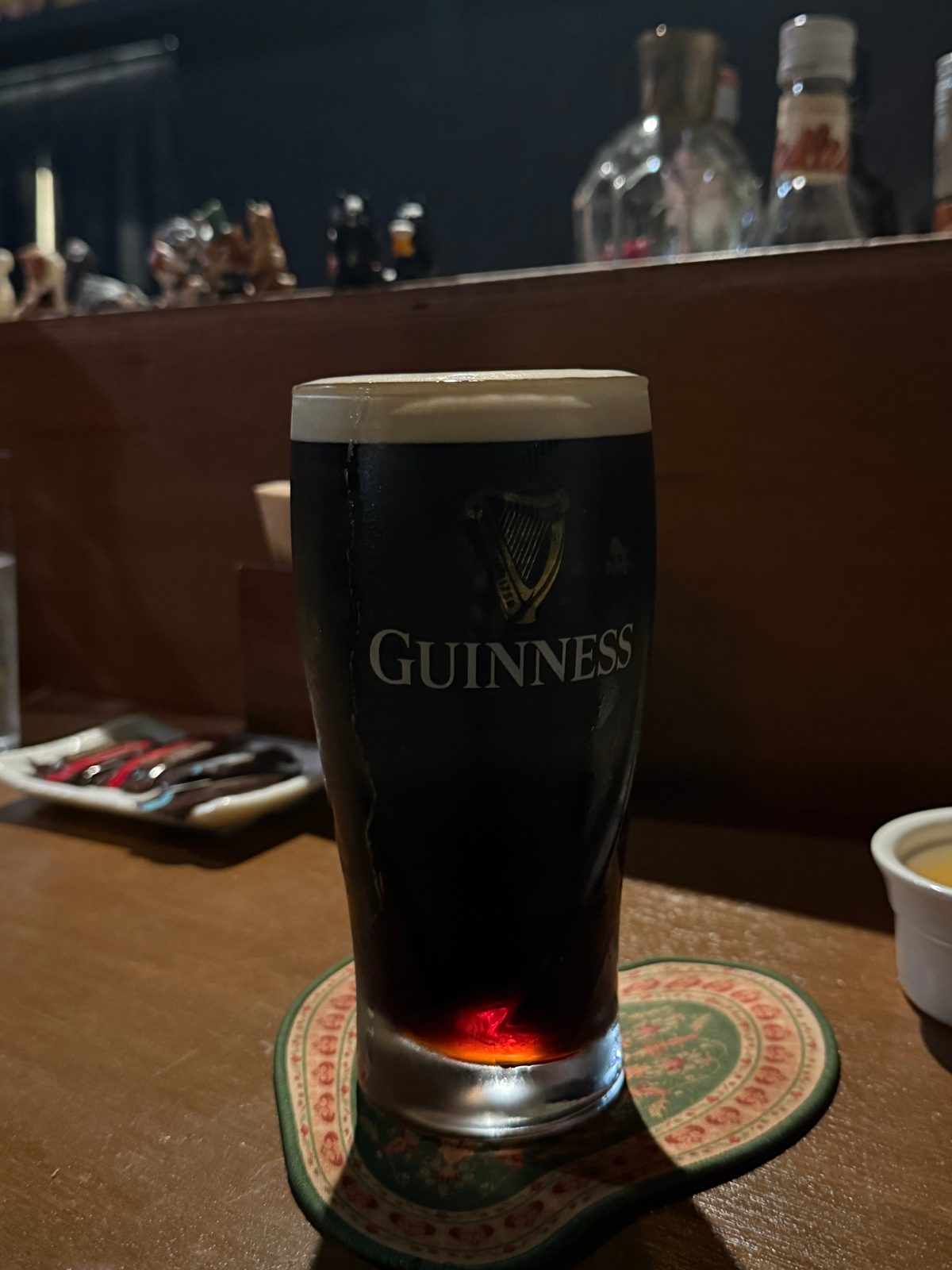 A glass of Guinness on a coaster on the bar