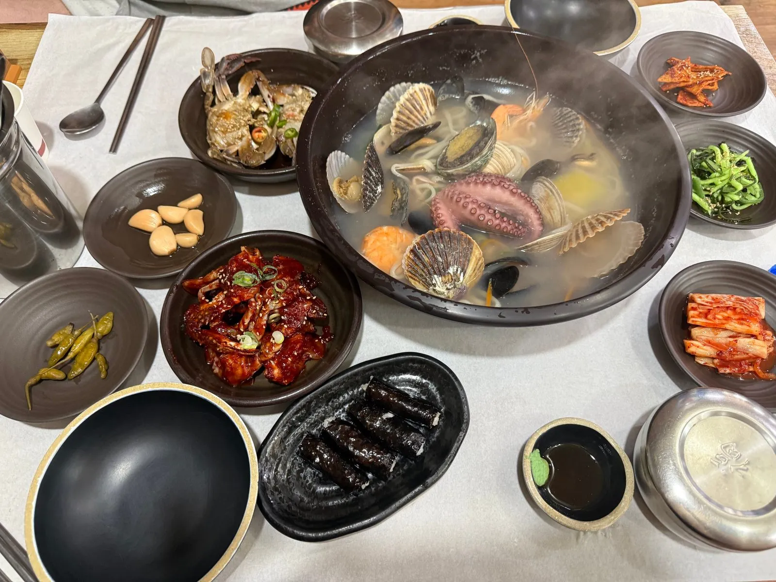 가운데에 해물 칼국수 냄비가 놓이고 둘레에 게장과 반찬 그릇이 놓인 상차림