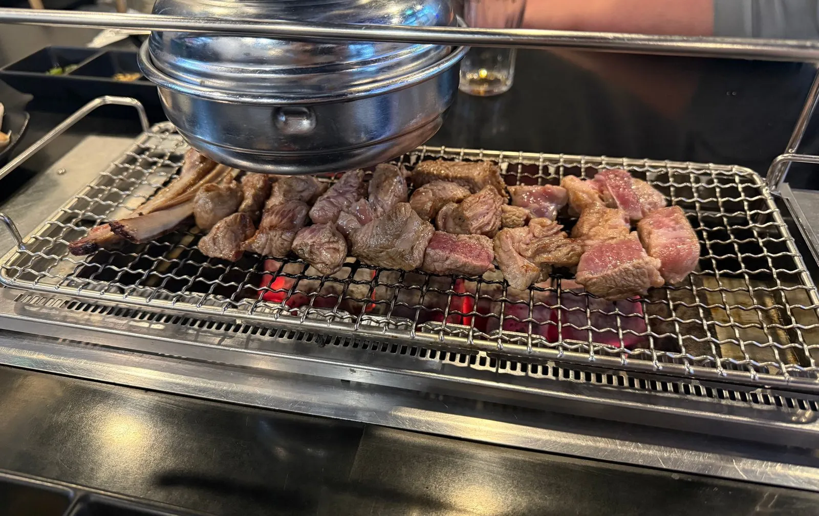Lamb ribs cooking on a wire grill over charcoal