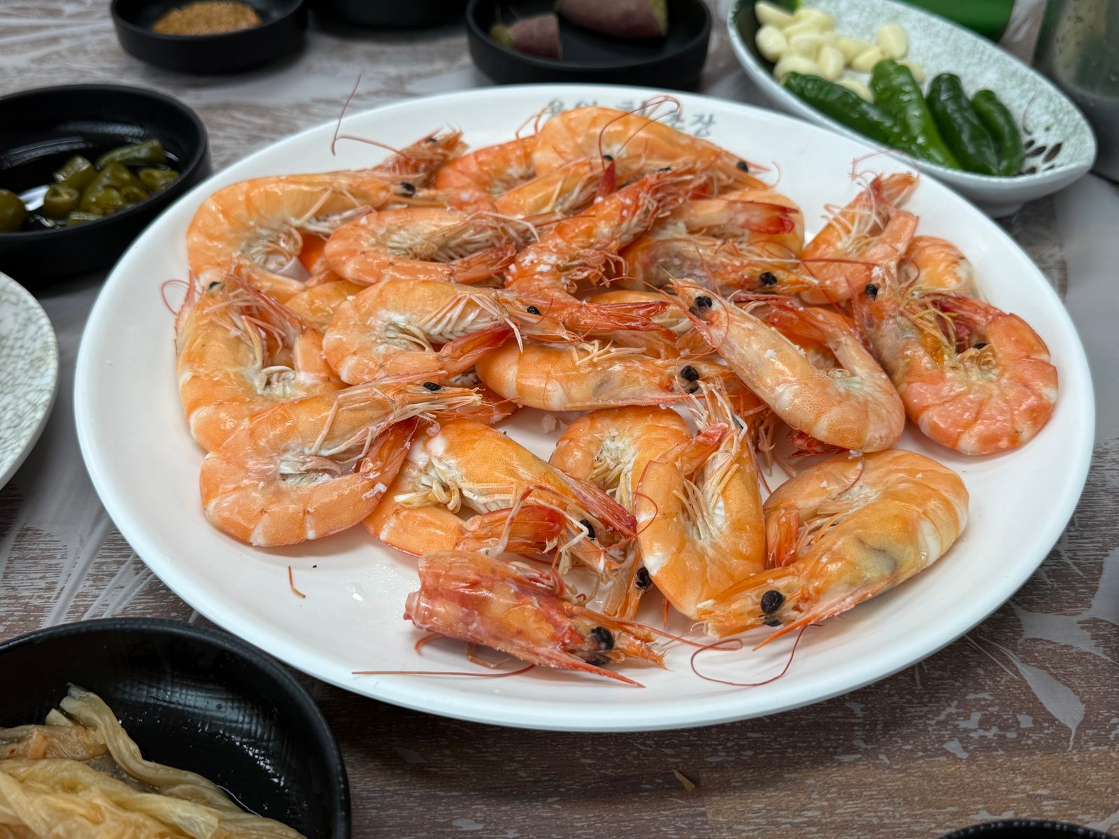 A white plate piled with salt-grilled shrimp