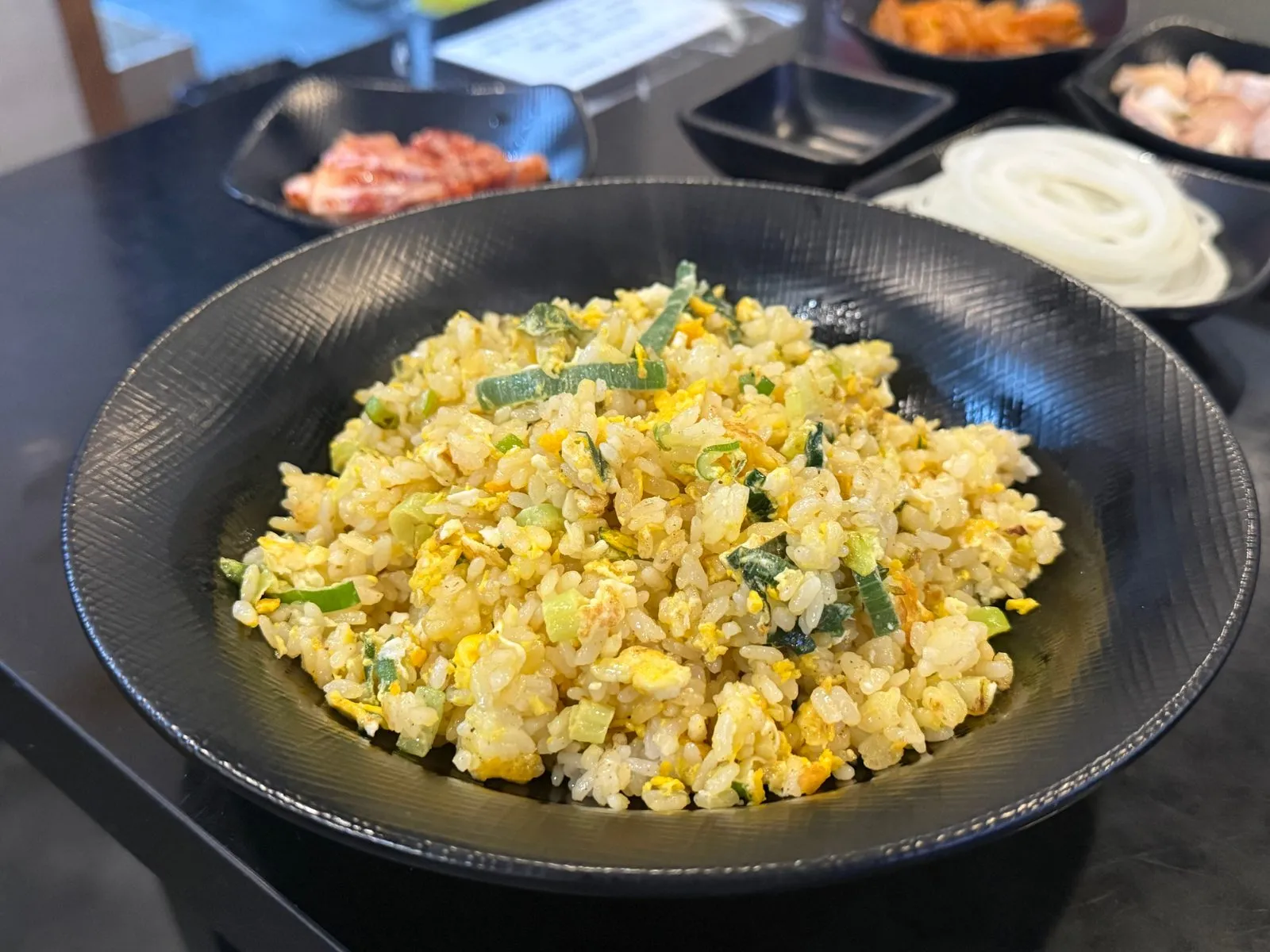 Yellow egg fried rice in a black bowl