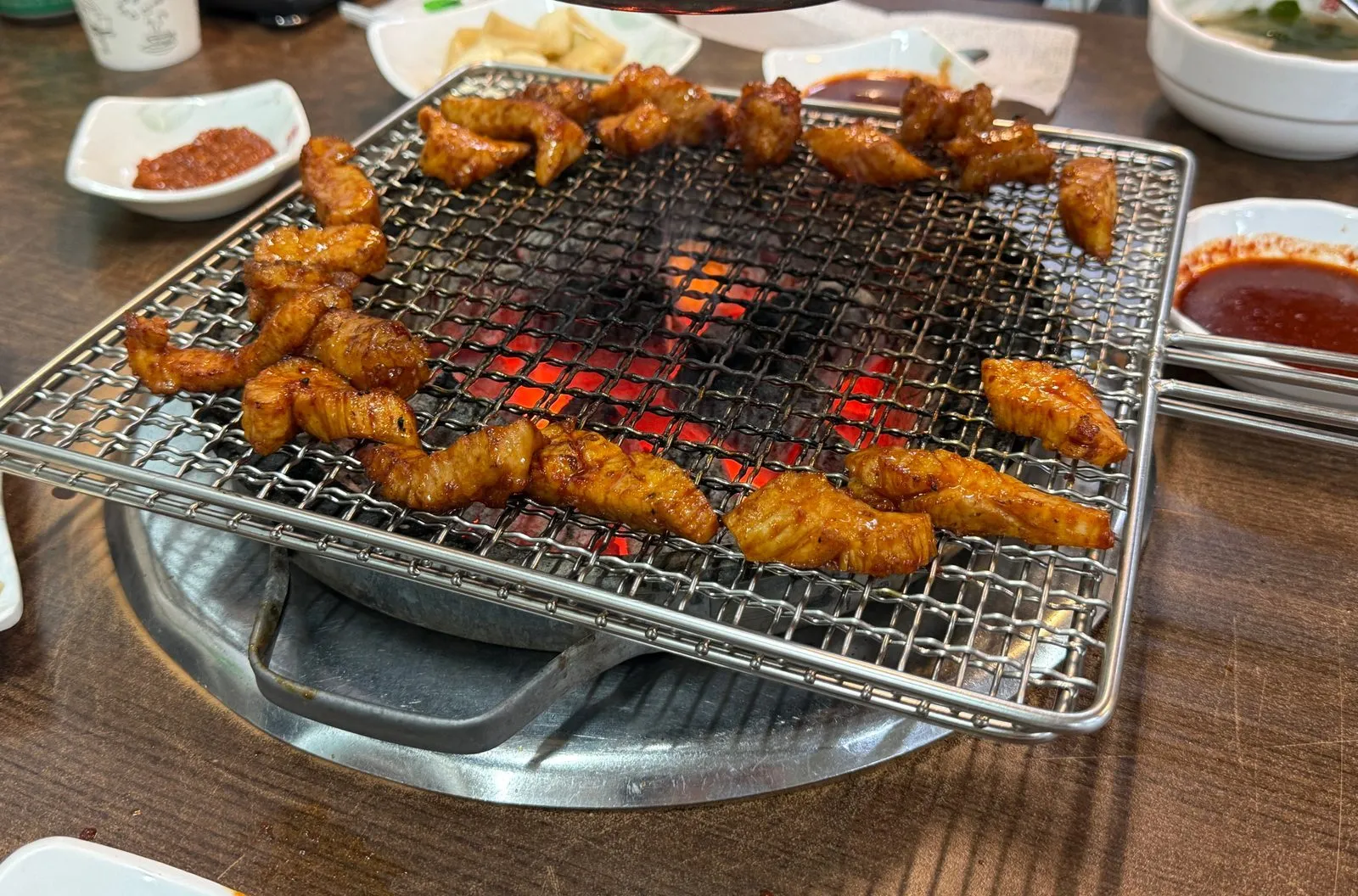 Seasoned beef tripe and large intestine cooking on a wire grill over charcoal