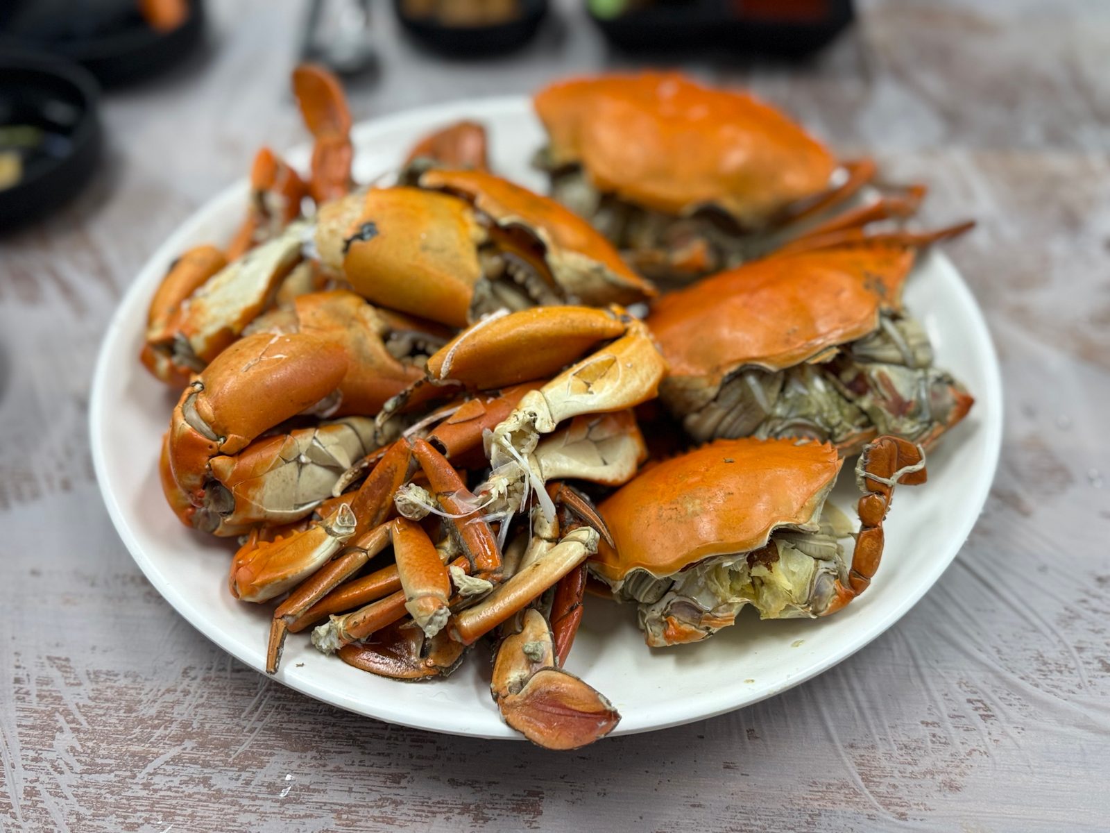 Orange steamed mud crabs piled on a white plate