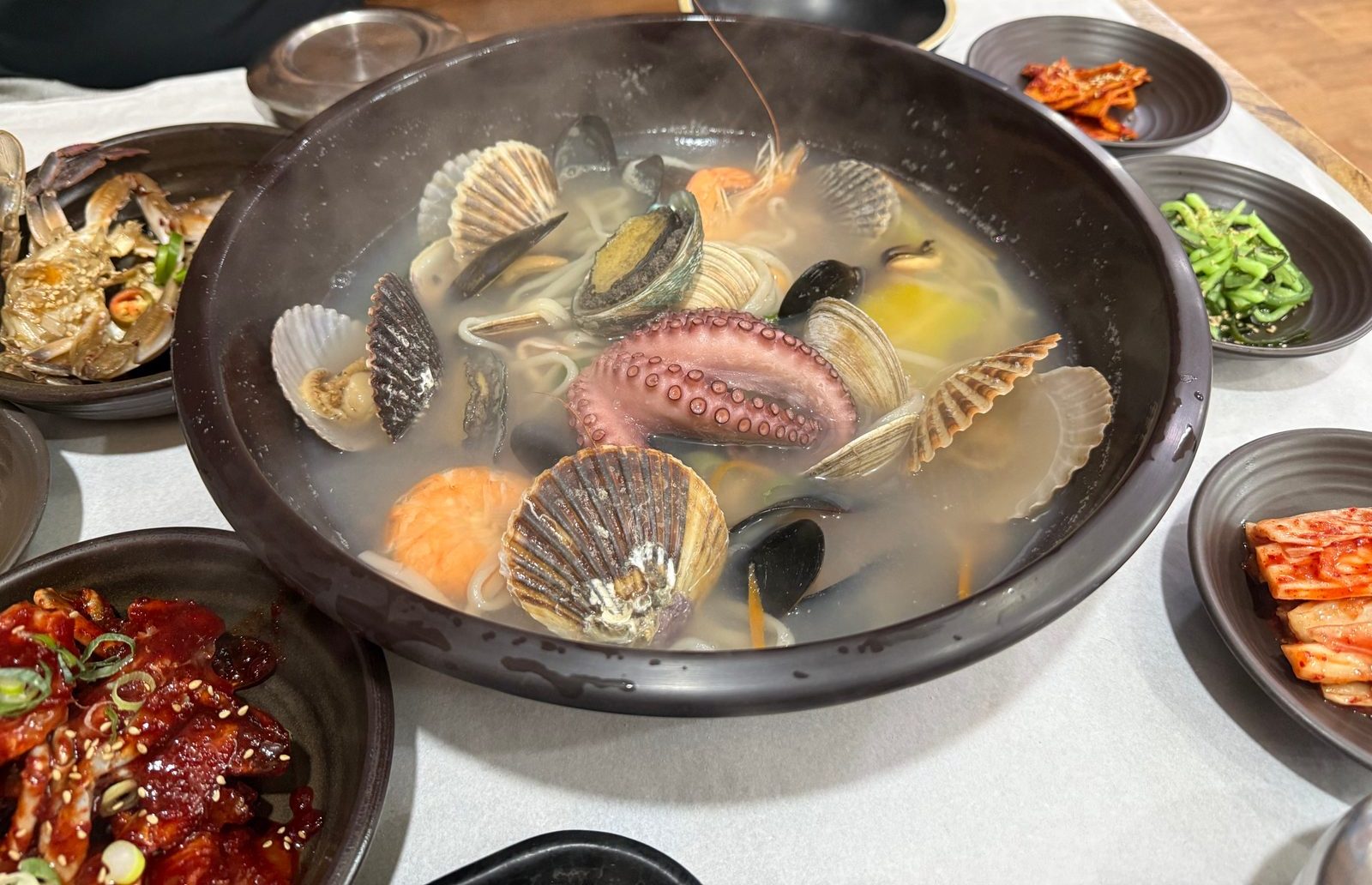 A pot of seafood noodle soup full of clams and octopus