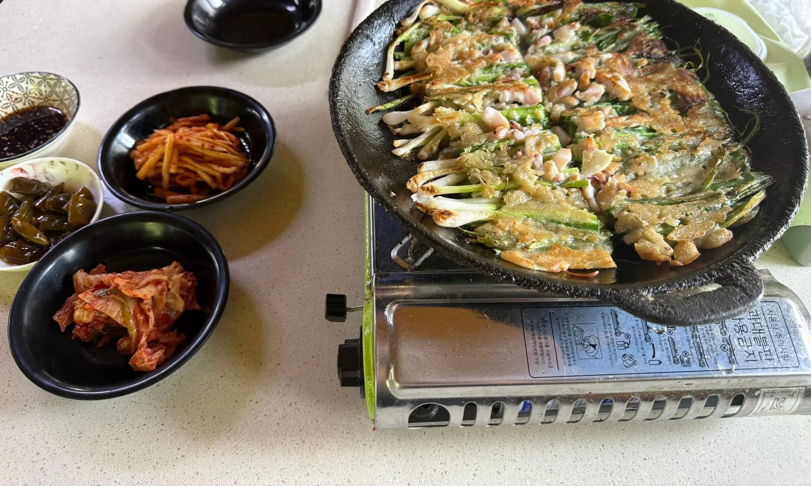 검은 팬에 담겨 나온 파전과 작은 그릇에 담긴 반찬들
