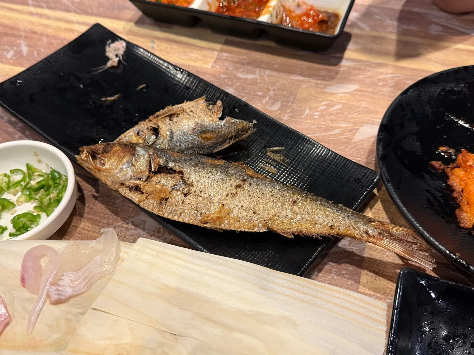 A whole grilled fish on a black plate