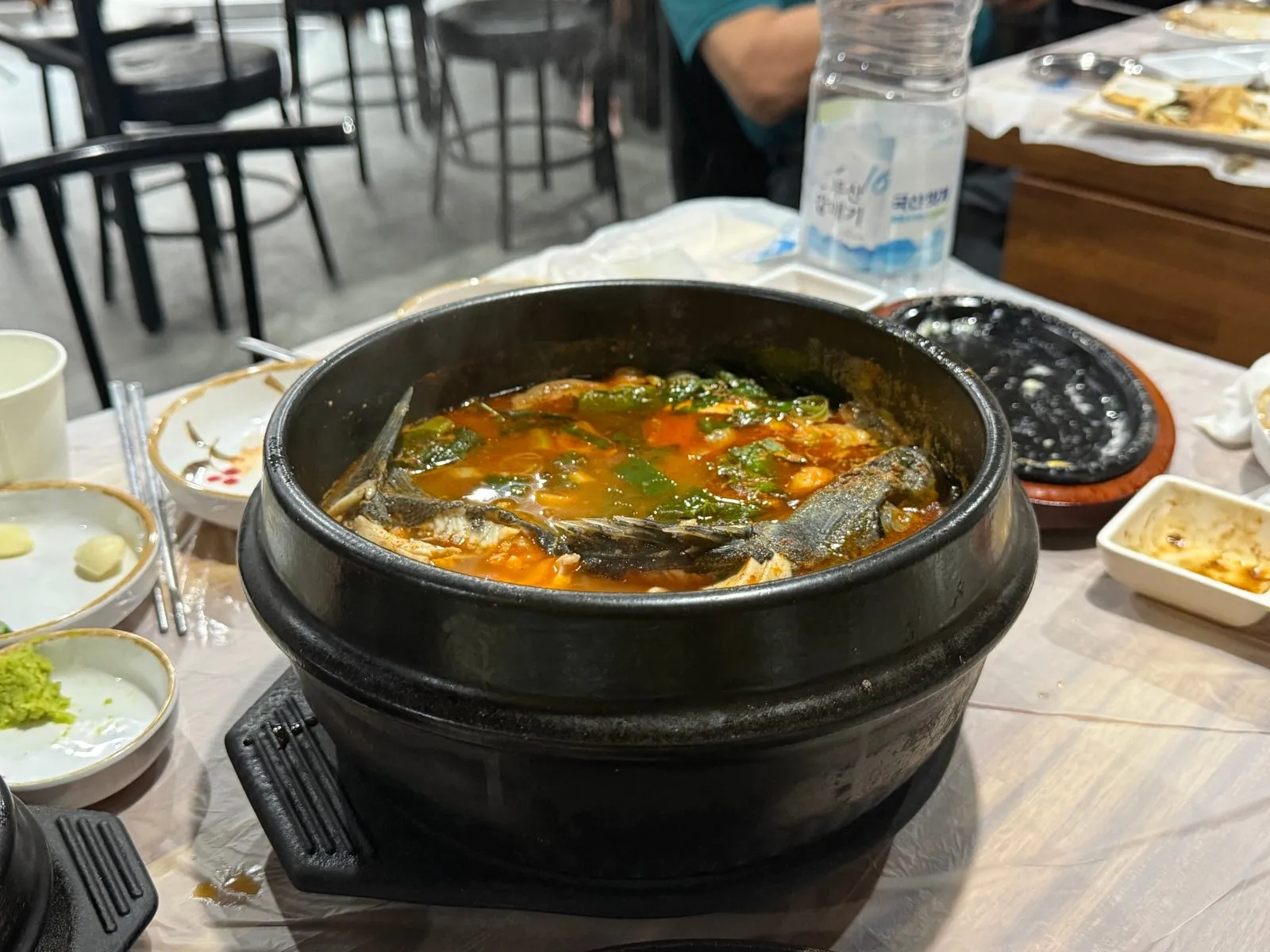 A red spicy fish stew boiling in an earthenware pot