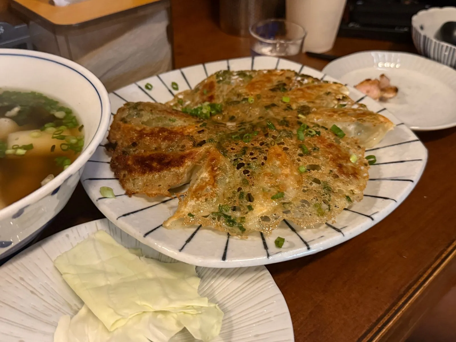 Pan-fried gyoza joined by a crisp lacy crust on a striped plate